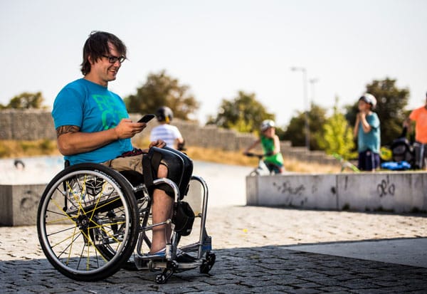 Mann im Rollstuhl mit Smartphone in der Hand